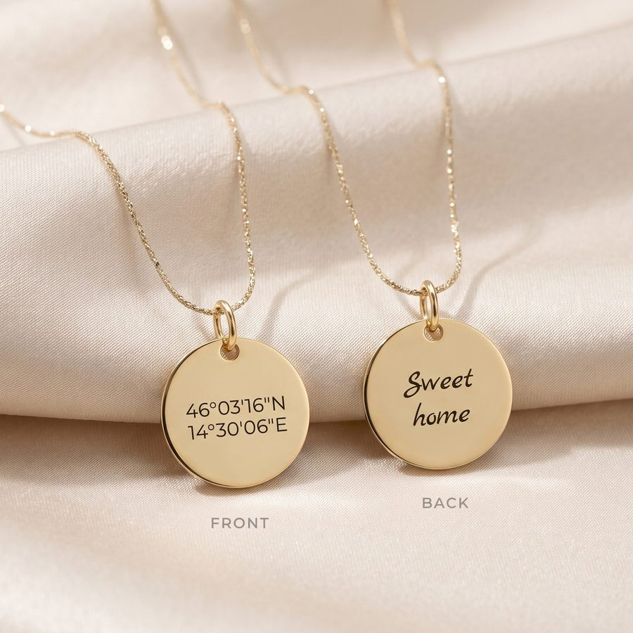 Two gold round pendant necklaces displayed on a soft beige satin fabric. One pendant shows engraved coordinates labeled FRONT, and the other shows the word 'Sweet home' labeled BACK.